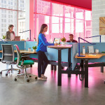 Pink lighted desking area with people talking to each other